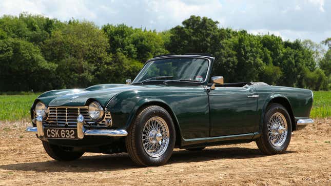 A photo of a green Triumph sports car in a field. 