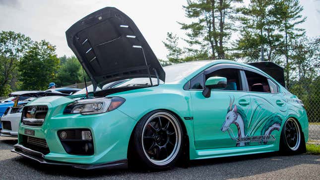 A photo of a mint green modified Subaru. 