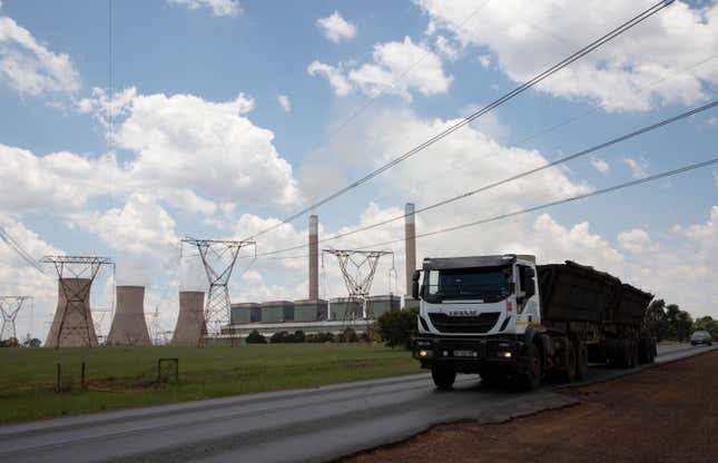 FILE — A coal truck, right, passes the coal-powered Duvha power station, near Emalahleni (formerly Witbank) east of Johannesburg, Thursday, Nov. 17, 2022. South African authorities say they have carried out search and seizure operations across five provinces to break up a huge coal-smuggling syndicate that cost the country more than $26 million and contributed to the breakdown of some of its state-owned power stations and an ongoing power crisis. (AP Photo/Denis Farrell/File)