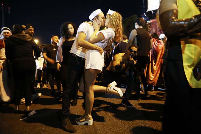 Revelers kiss, posing as the subjects in the famous Times Square kiss  photo by Alfred Eisenstaedt, at the annual Hollywood Carnaval street  party on October 31, 2018, in West Hollywood, California.
