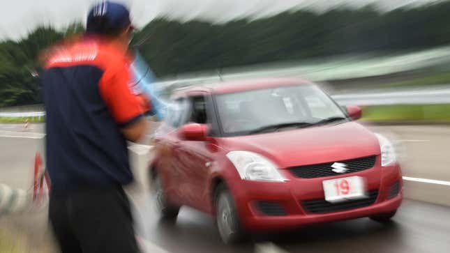 A photo of an instructor watching a car at a Japanese driving school. 