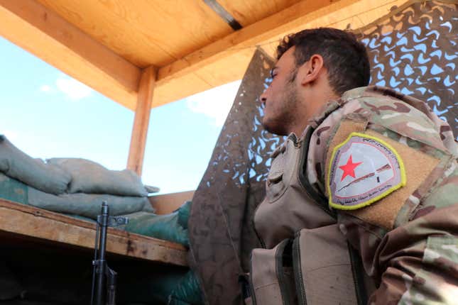 On October 7th, a fighter from the U.S.-backed Kurdish-led Syrian Democratic Forces, SDF, stands guard inside a post where U.S. troops were based, in Tal Abyad. Tal Abyad is currently under attack by Turkish air and artillery.
