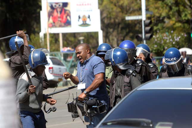 A cameraman is assaulted by police during demonstrations in Harare on Aug. 3, 2016.