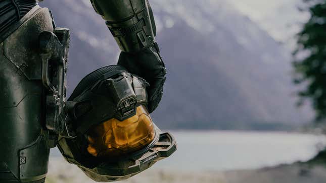 Master Chief stands on the Halo ring, helmet in hand.