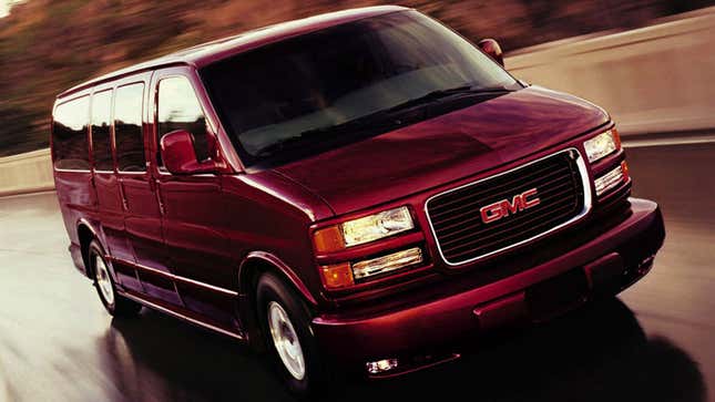 A photo of a red GMC van driving on a highway. 