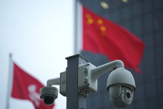 Chinese and Hong Kong flags fly near surveillance cameras, in Hong Kong