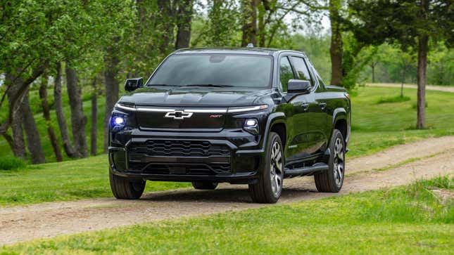 A front 3/4 view of the 2024 Silverado EV RST driving on a dirt trail.