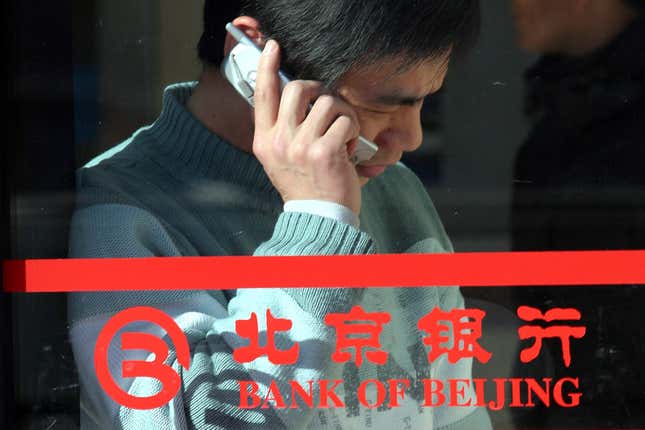 FILE - A Chinese man uses his mobile phone near the logo for the Bank of Beijing in Beijing Jan. 29, 2005. The former chairman of state-owned Bank of Beijing is under investigation for corruption, according to an official notice Friday, March 1, 2024, the latest in a series of graft investigations focused on the country&#39;s financial sector. (AP Photo, File)