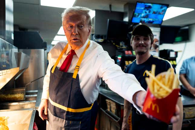 Politics tamfitronics Donald Trump, in a black apron, hands McDonald's fries to someone