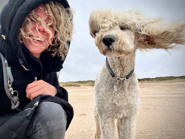 A human and a dog, both with their curly hair obstructing their faces.