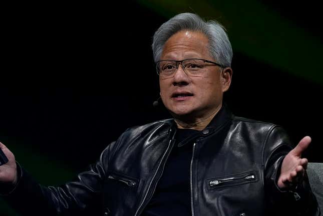 Jensen Huang wearing a black leather jacket sitting in a chair speaking with his hands up