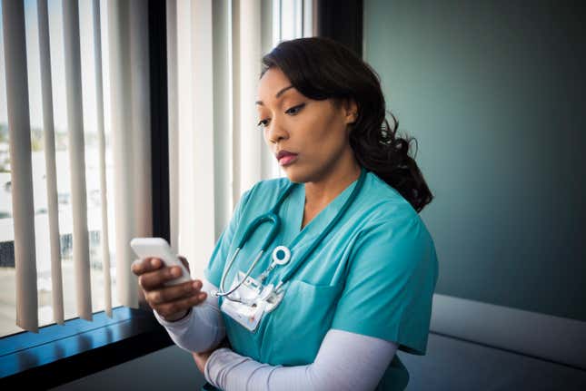 Black woman healthcare worker looking at phone