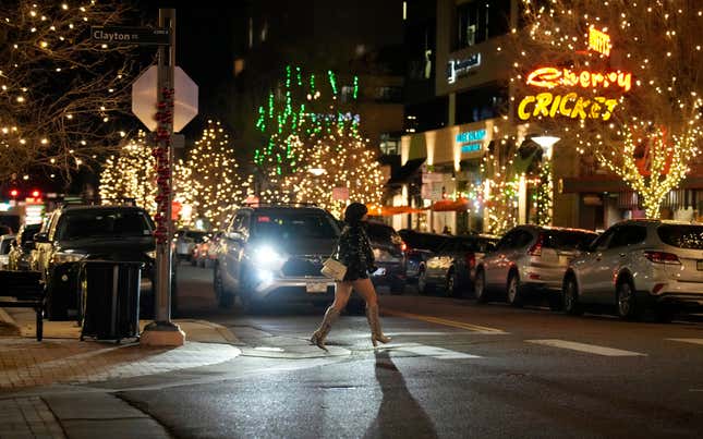 Holiday shopper crosses First Avenue in the Cherry Creek North shopping district late Friday, Dec. 15, 2023, in Denver. (AP Photo/David Zalubowski)