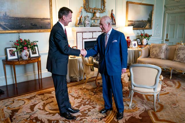 King Charles III, right, shakes hands with the Chancellor of the Exchequer, Jeremy Hunt, left, in the private audience room at Buckingham Palace, London, England, Tuesday, March 5, 2024. (Aaron Chown/PA via AP)