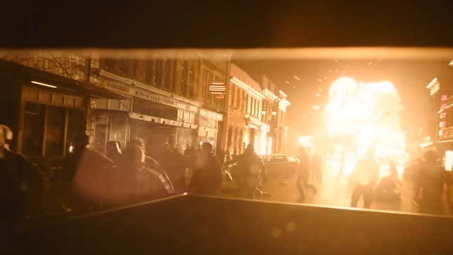 An explosion sends people running down a street.