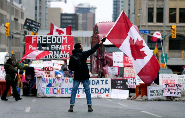 FILE - A protester waves a Canadian flag in front of parked vehicles at a protest against COVID-19 measures that has grown into a broader anti-government protest, in Ottawa, Ontario, Feb. 11, 2022. In a decision released Tuesday, Jan. 23, 2024, a Canadian judge ruled that the government’s use of the Emergencies Act to quell weeks of protests by truckers and others angry over COVID-19 restrictions in 2022 was unreasonable and unconstitutional. (Justin Tang/The Canadian Press via AP, File)