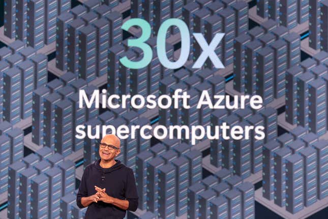 Satya Nadella speaking with his hands clasped together in front of a backdrop that says 30X Microsoft Azure supercomputers