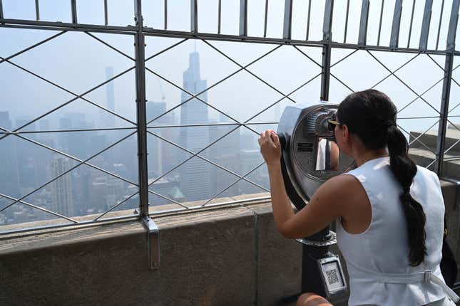 La gente visita la plataforma de observación del edificio Empire State mientras el humo de los incendios forestales canadienses cubre el horizonte de Manhattan el 30 de junio de 2023 en  Ciudad de Nueva York.