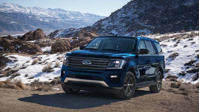 A photo of a blue Ford Expedition SUV driving on a snowy path. 