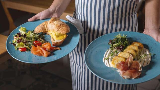 Restaurant server holding two plates of breakfast food