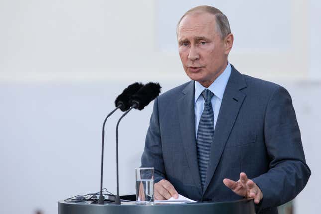 Vladimir Putin speaks into microphones.