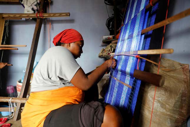 A woman, using a local weaving tool, weaves traditional attire in a shop along a street in Lagos, Nigeria, August 10, 2017.REUTERS/Akintunde Akinleye