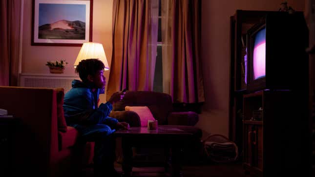 A teenager stares at a glowing TV set