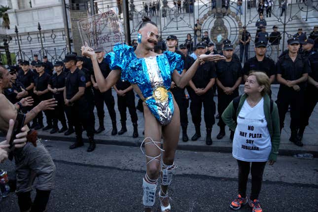 Vick Teker, dressed in a national flag outfit holding a sign with a message that reads in Spanish: &quot;I am art and I am hungry&quot;, and a woman wearing a T-shirt with a message that reads: &quot;There is no money. I am retired&quot;, take part in a demonstration outside Congress as part of a national strike to protest the economic and labor reforms proposed by Argentine President Javier Milei in Buenos Aires, Argentina, Wednesday, Jan. 24, 2024. (AP Photo/Rodrigo Abd)