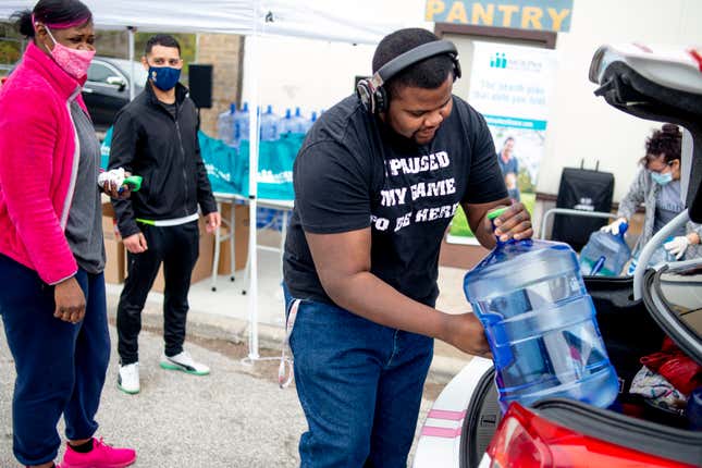 FILE - R-Mon Ford, 23 of Flint, puts freshly filled five-gallon jugs of water into his mother L'Tonya Payne's trunk on the eve of the seventh anniversary of the Flint water crisis during a water distribution on Saturday, April 24, 2021 at the Latinx Technology & Community Center in Flint, Mich. A second contractor says it has reached a $25 million settlement over its role in Flint's lead-contaminated water scandal. Boston-based Veolia North America said Thursday, Jan. 31, 2024, that the class-action litigation agreement includes payments of $1,500 for individual minors. (Jake May/The Flint Journal via AP, File)