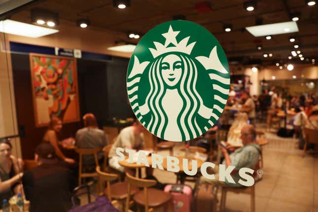 Logotipo de Starbucks en una puerta con personas sentadas en el interior fuera de foco