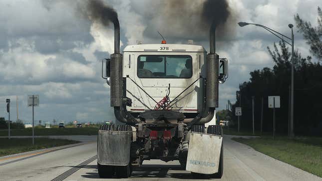 A photo of a tractor trailer exhausting black smoke while driving