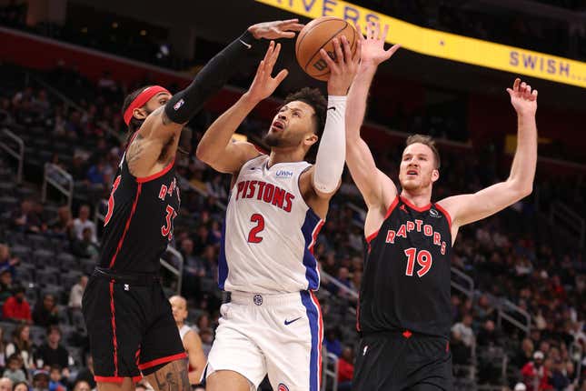 DETROIT, MICHIGAN - DECEMBER 30: Cade Cunningham #2 of the Detroit Pistons drives to the basket between Gary Trent Jr. #33 and Jakob Poeltl #19 of the Toronto Raptors during the first half at Little Caesars Arena on December 30, 2023 in Detroit, Michigan. NOTE TO USER: User expressly acknowledges and agrees that, by downloading and or using this photograph, User is consenting to the terms and conditions of the Getty Images License Agreement. (Photo by Gregory Shamus/Getty Images)