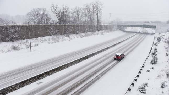 A photo of a single car driving on an empty highway. 