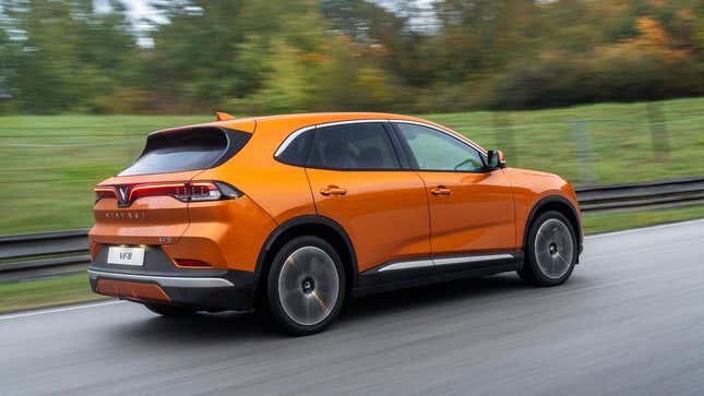 An orange VinFast VF8 drives on a closed course in the rain.