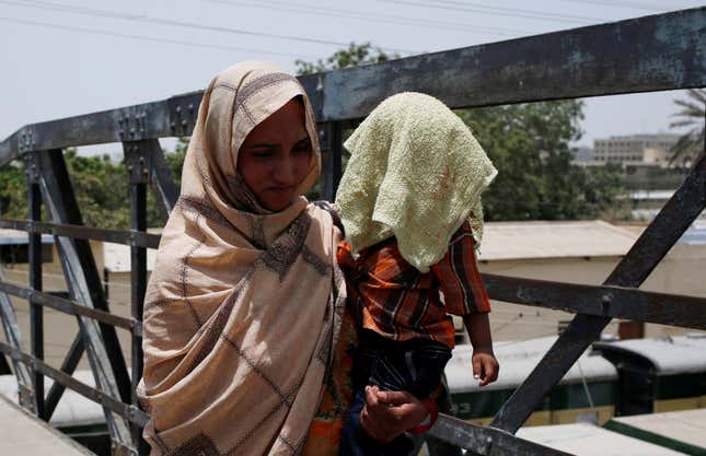 A mother holds her child, covered with a towel to avoid sunlight, on May 21.