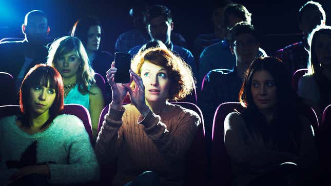 A photo shows a woman taking a picture in a crowded theater. 