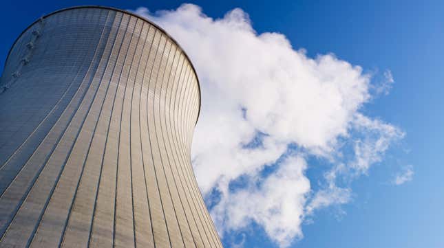 upward view of nuclear reactor with smoke coming out of it against a blue sky