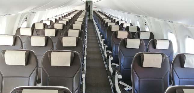 Rows of empty airplane seats on a plane i 2020. The seats are grey with white headrests.