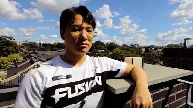 Kim wears a Fusion jersey on top of a building with clouds and trees in the background. 