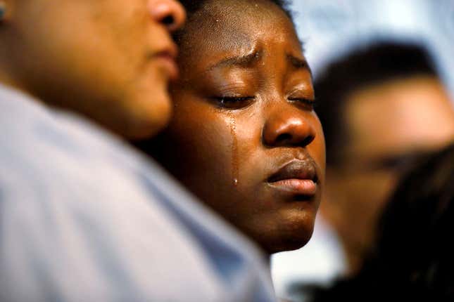 Tears stream down the cheeks of the daughter of Alfred Olango while she is embraced by her mother.