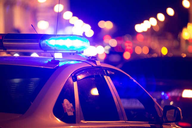 Blue light flasher atop of a police car. City lights on the background.