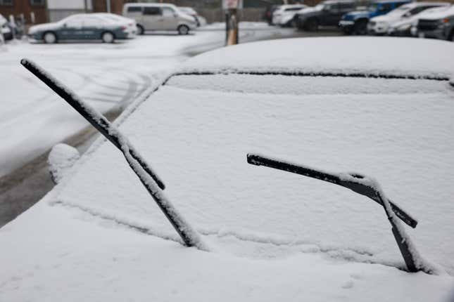 A parked car is pictured with its windshield wipers raised as snow falls in Toronto.