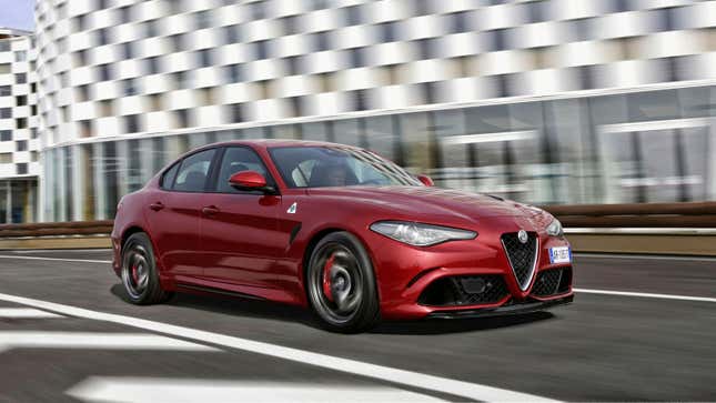 A photo of a red Alfa Romeo sedan driving on an empty road. 