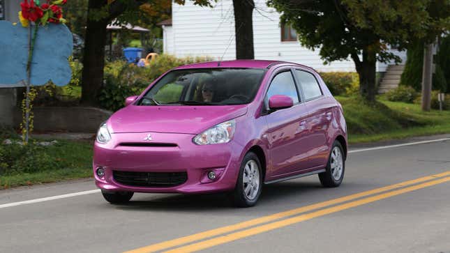 A pink Mitsubishi Mirage driving on a road. 