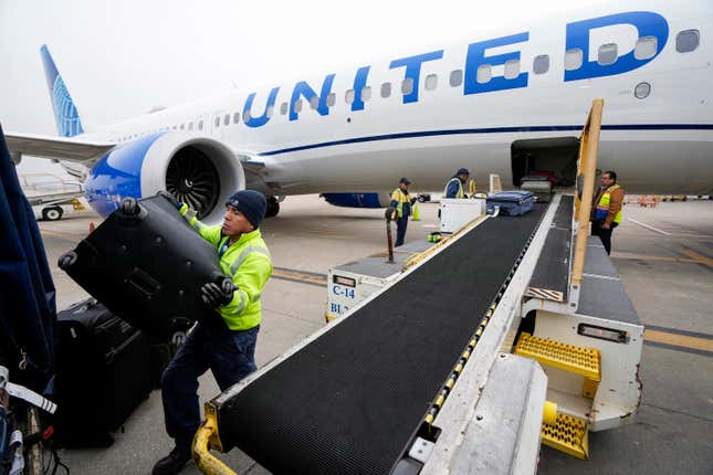 FILE - Juan Chavez handles baggage as is comes off a United Airlines aircraft upon landing at George Bush Intercontinental Airport on Thursday, Dec. 21, 2023, in Houston. United Airlines said Friday, Feb. 23, 2024, that it is raising its fees for checking bags, following a similar move earlier this week by American Airlines. (Brett Coomer/Houston Chronicle via AP, File)