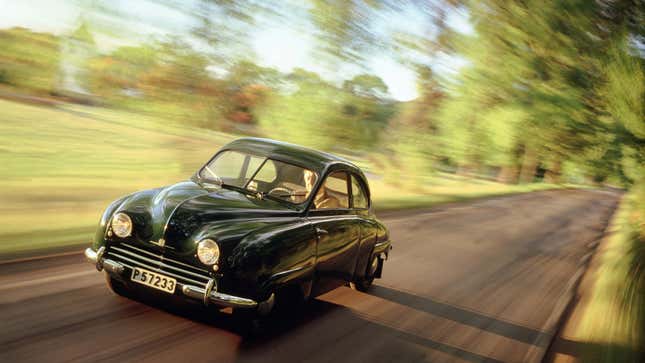 A photo of a vintage Saab 92 driving on a country road. 