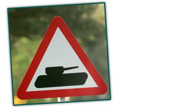 A photo of a triangular sign with a tank in the midle. 