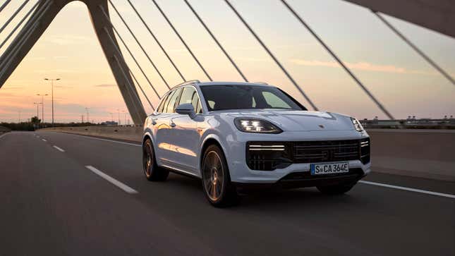 A white 2024 Porsche Cayenne Turbo E-Hybrid drives across a modern suspension bridge at sunset