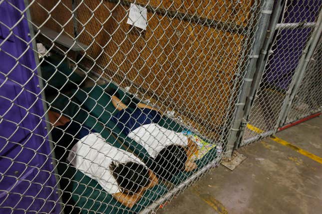 Two female detainees sleep in a holding cell.