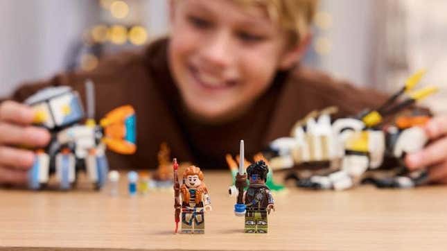 Two Horizon Lego mini-figures stand on a table. 